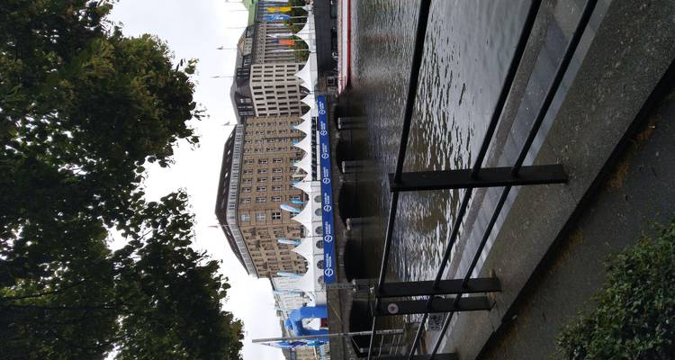 Scène de canal avec des tentes d'événement et des bâtiments historiques de la ville se reflétant dans l'eau à Hambourg