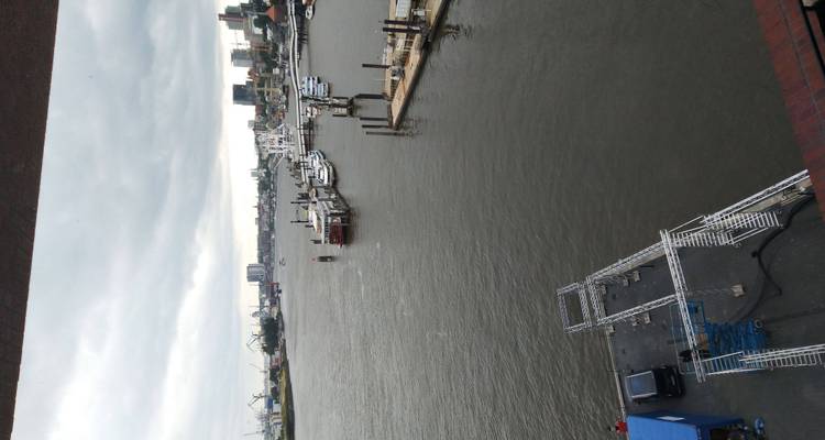 Vue panoramique sur le fleuve Elbe avec quais, grues et skyline urbain sous un ciel nuageux