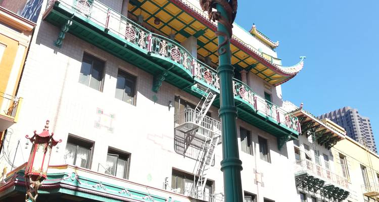 Façade colorée d'immeuble de Chinatown avec balcon orné et escalier de secours