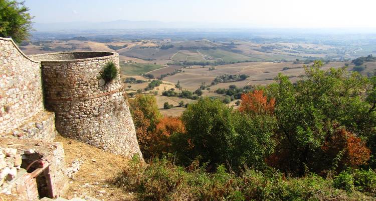 Bastion de pierre rond ancien surplombant une vaste vallée rurale parsemée d'arbres d'automne