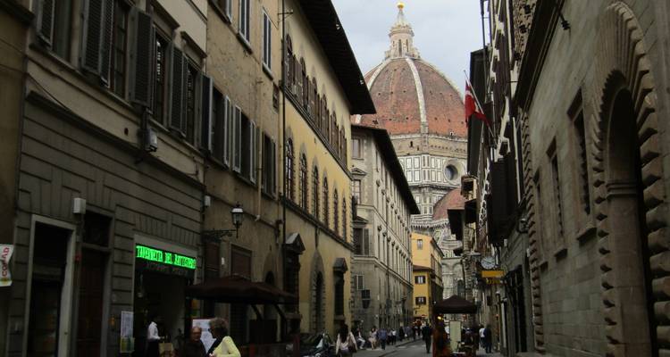 Rue historique de Florence avec des boutiques et aperçu du dôme du Duomo au bout de la perspective