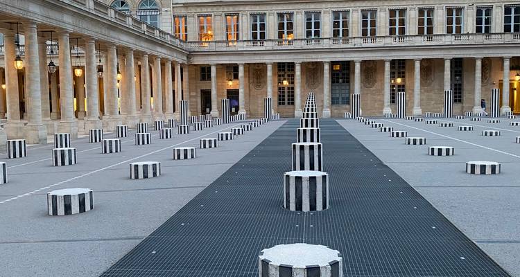 Les colonnes striées en noir et blanc de la cour du Palais-Royal forment des rangées géométriques dans la douce lumière du soir.