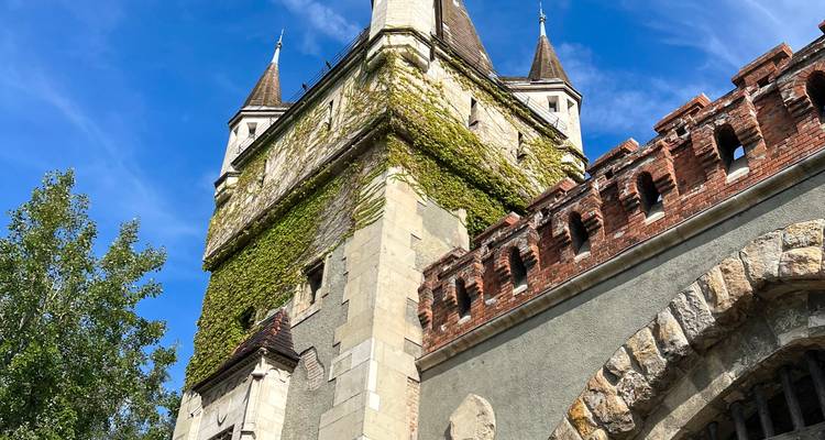 Efeuberankte Steinturm der Burg Vajdahunyad vor einem leuchtend blauen Himmel.