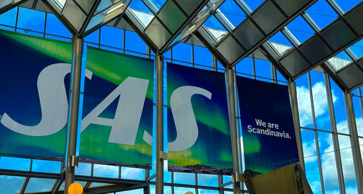 Grande banière SAS « We are Scandinavia » à l'intérieur d'un terminal d'aéroport aux toits vitrés.