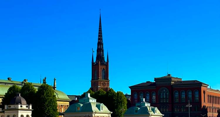 Le haut clocher de l'église Riddarholmen s'élevant au-dessus des bâtiments de Stockholm contre un ciel bleu profond.