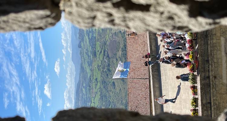 scène de cour vue à travers une brèche en pierre avec le drapeau de Saint-Marin flottant et des visiteurs en dessous