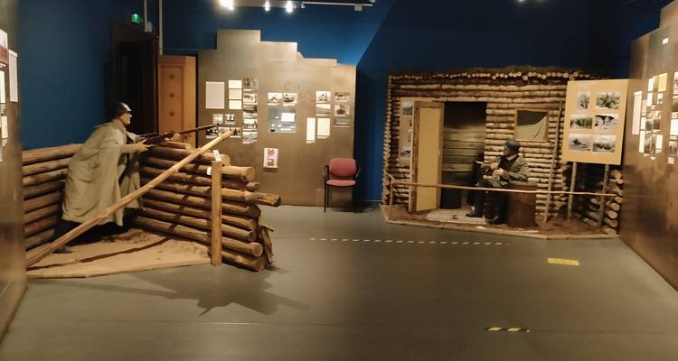 Indoor war museum diorama showing soldiers in wooden trench fortifications.