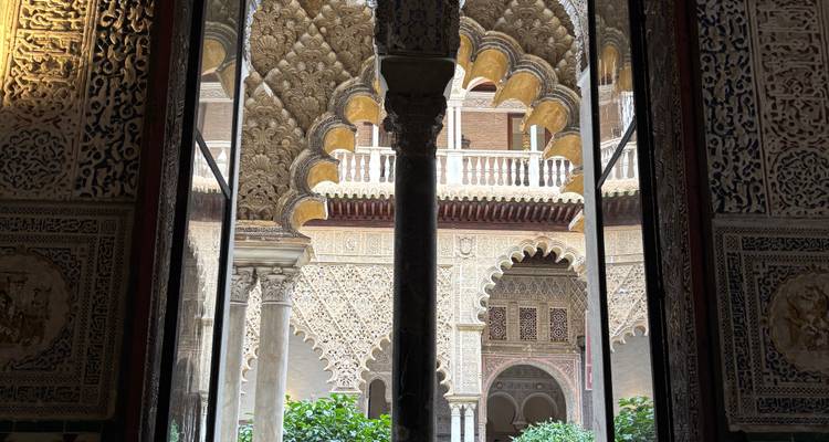 Des arches de style islamique complexes et des motifs géométriques encadrant une cour palatiale.