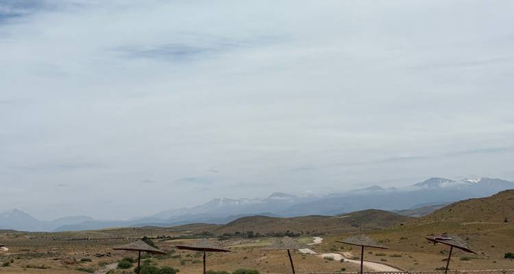 Paisaje árido ondulante con sombrillas dispersas y montañas a lo lejos