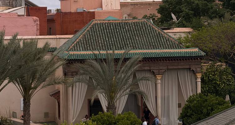 Edificio tradicional con techo de tejas verdes y cortinas translúcidas rodeado de palmeras