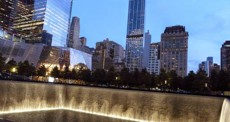 Evening view of the 9/11 Memorial waterfall pool framed by modern skyscrapers