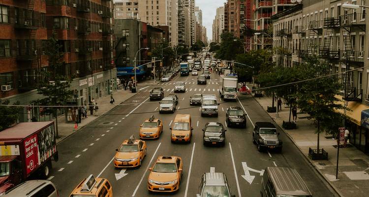 Street-level view of New York traffic with signature yellow taxis moving along multi-lane avenue