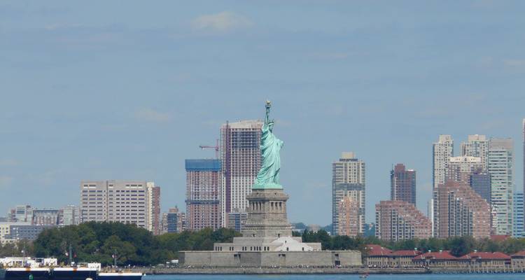 Distant view of the Statue of Liberty standing before New Jersey skyline across the water