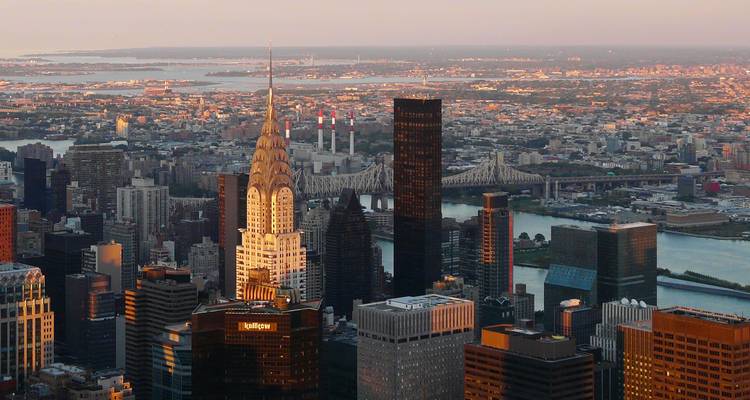 Golden hour aerial of Midtown Manhattan highlighting the Chrysler Building against a vast urban expanse