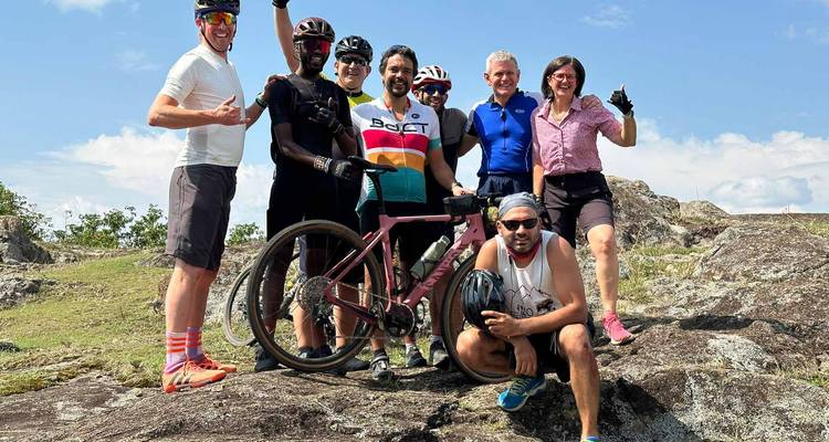 Les cyclistes posent fièrement avec leurs vélos au sommet rocheux sous un ciel bleu.