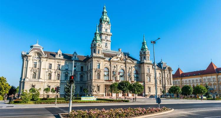Ayuntamiento de estilo neorrenacentista de Győr bañado en la luz matutina y nítida contra un cielo azul despejado.
