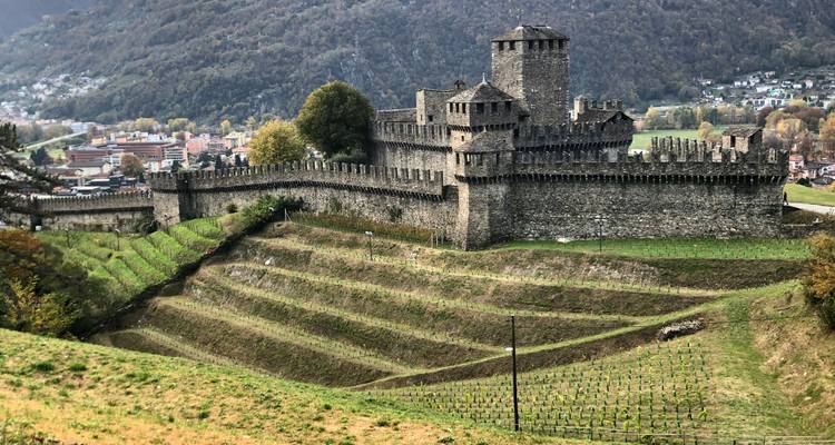 Los muros y torres de piedra medieval de Castelgrande se alzan sobre terrazas cubiertas de viñas y el pueblo de Bellinzona.