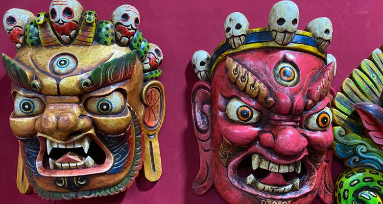 Gros plan sur des masques cérémoniels bhoutanais vibrants aux expressions féroces exposés sur un mur