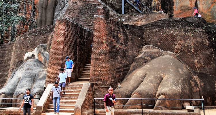 Bezoekers dalen af langs bakstenen trappen naast de kolossale leeuwenpoot ingang van de Sigiriya rotsenvesting.