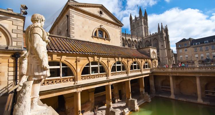 Complexe de thermes romains historiques avec statues et cathédrale en arrière-plan à Bath.