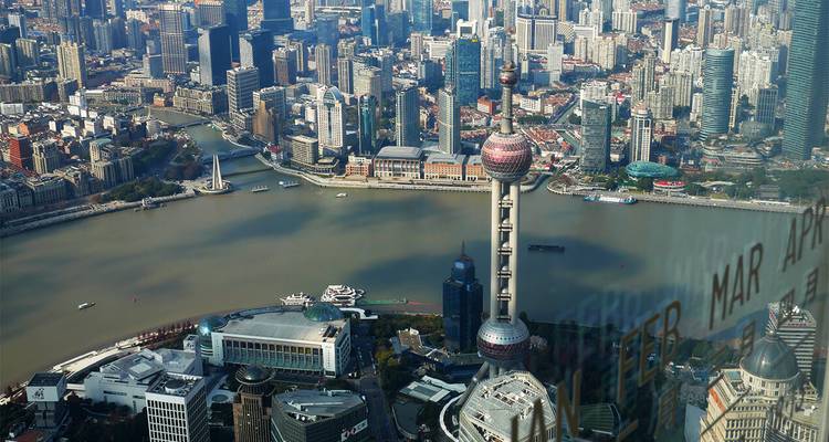 Vue aérienne diurne de Shanghai avec la Tour de la Perle de l'Orient s'élevant à côté du fleuve Huangpu sinueux.