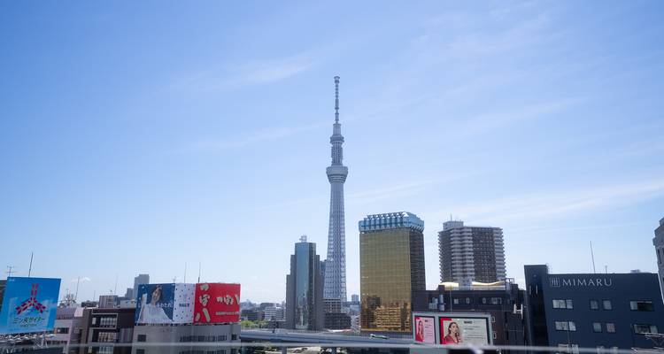 Skyline de Tokyo avec la tour élancée de Skytree s'élevant au-dessus des bâtiments modernes sous des cieux dégagés.