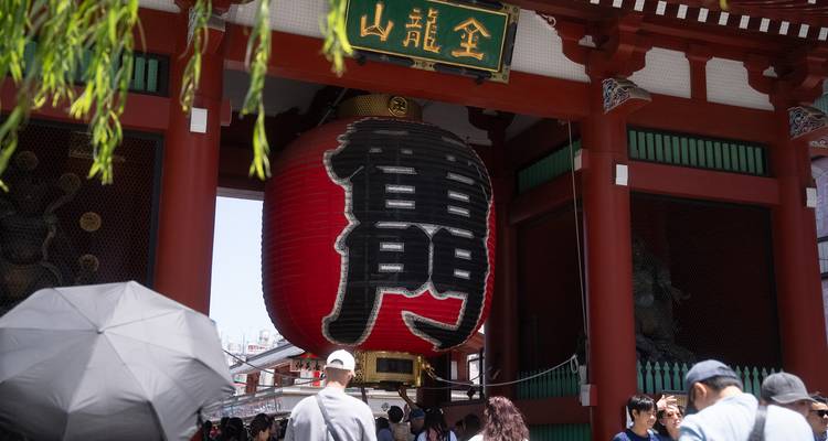 Entrée du Temple Senso-ji présentant l'immense lanterne en papier rouge avec des touristes rassemblés en dessous.