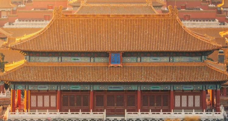 Fachada detallada de un gran salón de la Ciudad Prohibida bañado en luz cálida del atardecer.