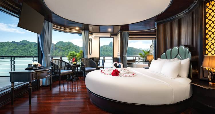 Cabine de croisière luxueuse et spacieuse avec lit rond, balcon et vue panoramique sur les îles calcaires.