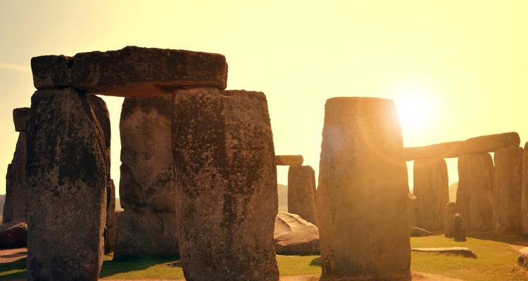 Iconic stones of Stonehenge silhouetted against a glowing sunrise sky.