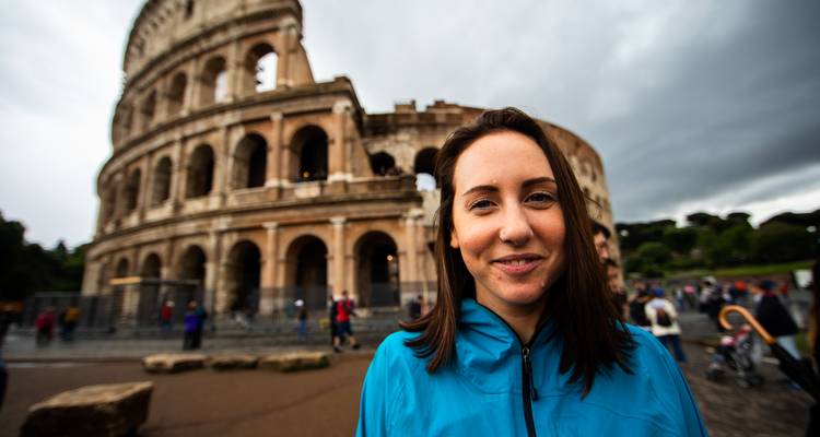 Porträt einer Frau in einer blauen Jacke, die vor dem Kolosseum an einem bewölkten Tag steht