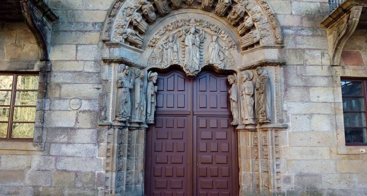 Portail de pierre sculptée avec des apôtres entourant des portes en bois cintrées à Santiago
