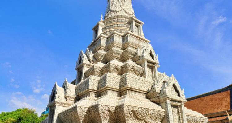 White intricately carved Buddhist stupa rising against a bright blue sky.