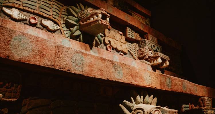 Gros plan de serpents en pierre finement sculptés et d'ornements provenant de la façade d'un ancien temple mésoaméricain.