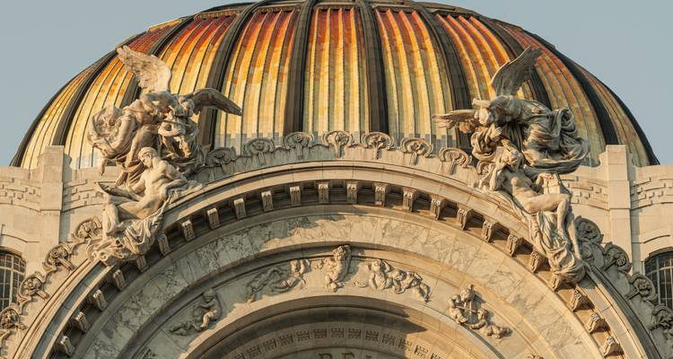 Vue détaillée du dôme doré carrelé et des anges sculptés au sommet du Palacio de Bellas Artes de Mexico.