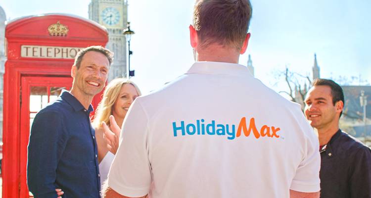 Tour group chats near London’s red telephone box with guide wearing HolidayMax polo.