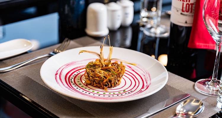 Gourmet-Platte mit fein gehacktem Gemüse auf einer künstlerischen Saucen-Spirale, serviert auf einem Restauranttisch