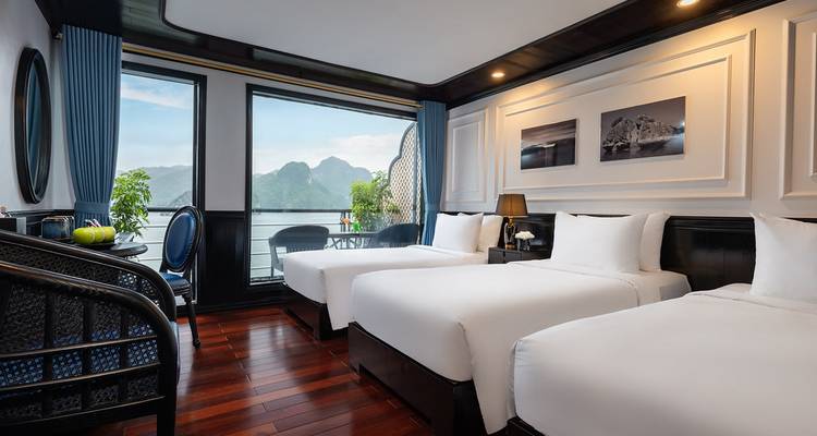 Cabine de croisière élégante avec trois lits et grandes fenêtres offrant une vue sur les pics de calcaire brumeux et les eaux calmes