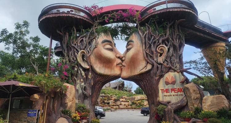 Large artistic sculpture of two tree-like faces kissing at a theme park entrance