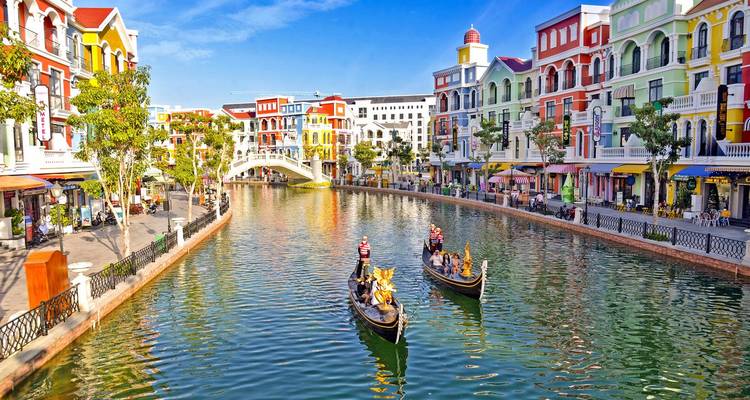 Colorful European-style canal lined with bright buildings and gondolas under a clear sky