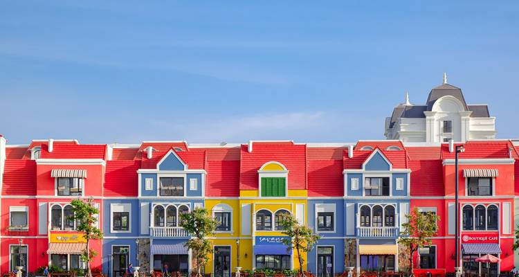Row of brightly painted European-style townhouses under a clear blue sky