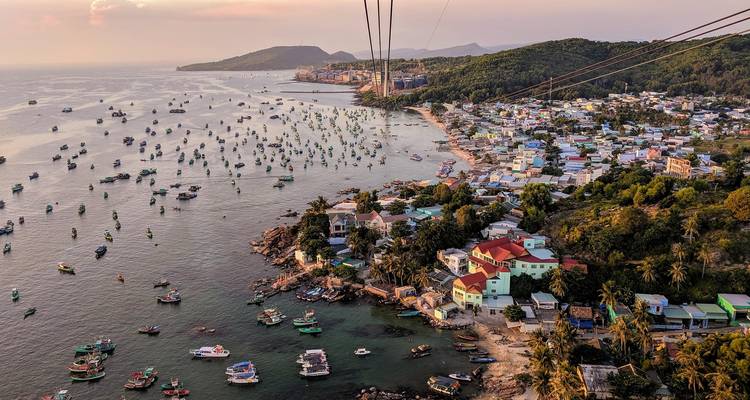 Aerial vista of a coastal town with hundreds of anchored fishing boats and cable-car wires overhead