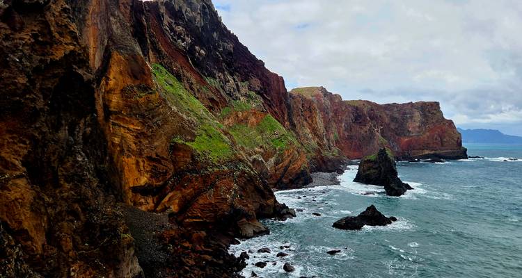 Des falaises colorées et stratifiées plongent dans les eaux tumultueuses de l'Atlantique le long d'une péninsule accidentée.