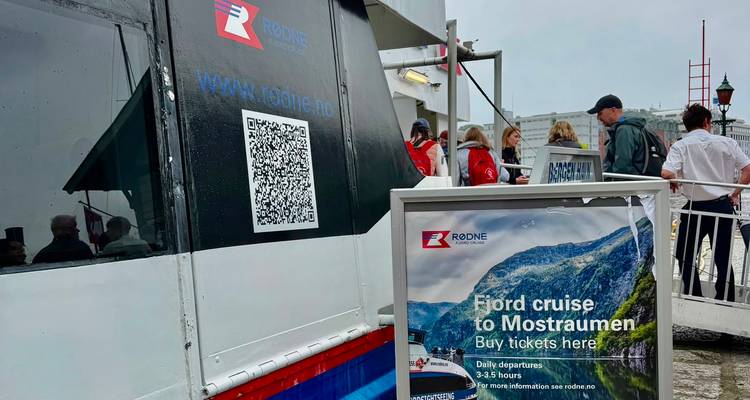 Zone d'embarquement pour un bateau de croisière dans les fjords avec signalisation des billets, code QR et passagers en attente dans la file d'attente.