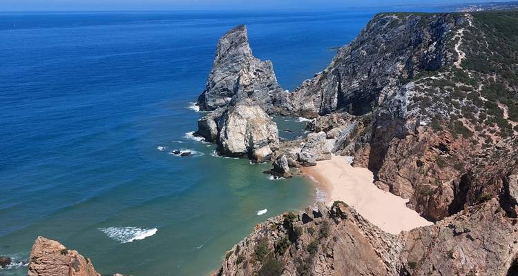 Dramatische rotsachtige landtong en verborgen zandige baai omgeven door turquoise Atlantische wateren
