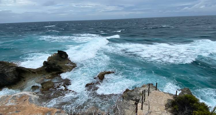 Rocky Caribbean cliff with powerful waves crashing and turquoise sea stretching to the horizon.