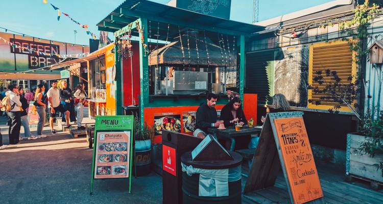 Marché animé de street-food en plein air avec des étals colorés, des menus et des clients savourant leurs repas