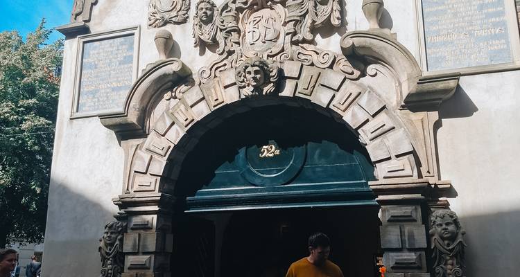 Arco de piedra decorativa con tallas intrincadas y una persona de pie en sombra parcial