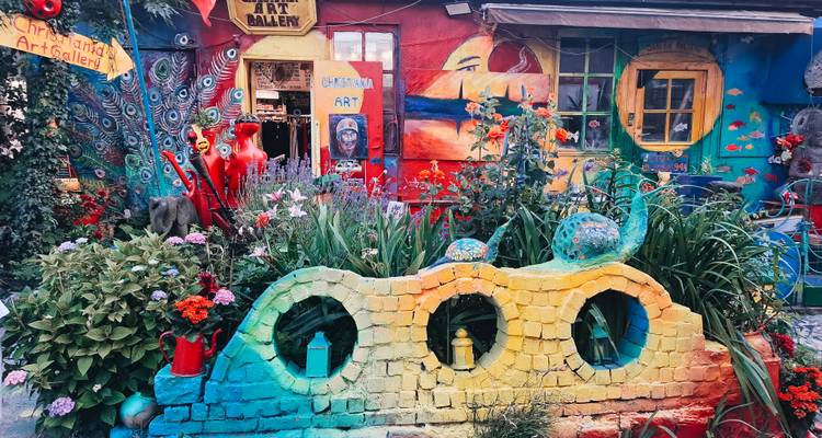 Vibrante jardín de patio con pared pintada de arcoíris, flores coloridas y arte peculiar