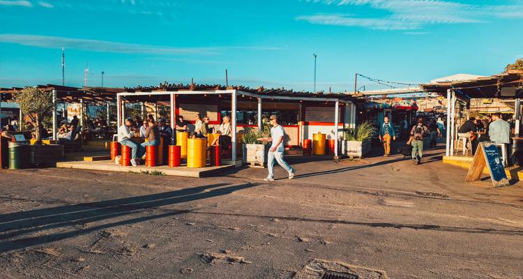 Multitud disfrutando por la noche de los puestos de comida al aire libre con barriles coloridos bajo un cielo despejado